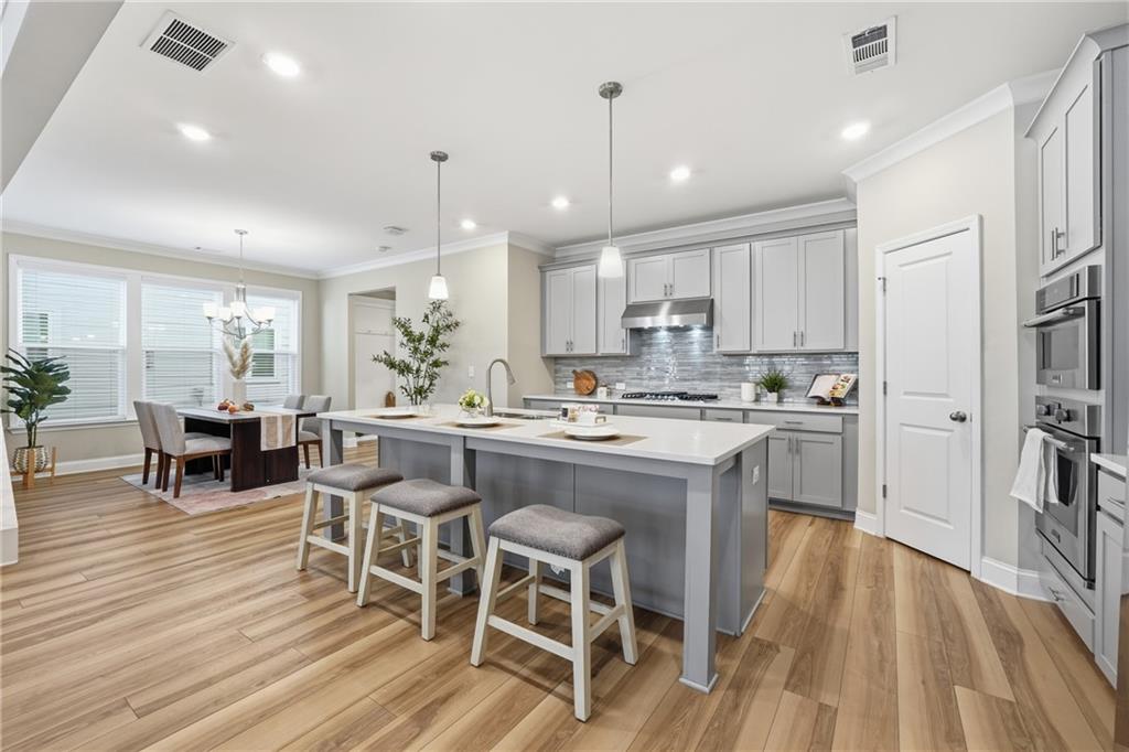 4183 Valtek Court Suwanee, GA 30024 - Photo 13 of 46 a kitchen with stainless steel appliances kitchen island granite countertop a table chairs sink and cabinets