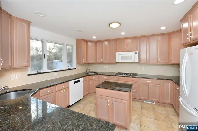 a kitchen with stainless steel appliances granite countertop a stove a sink and a microwave