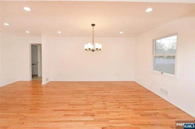 a view of kitchen and empty room with wooden floor