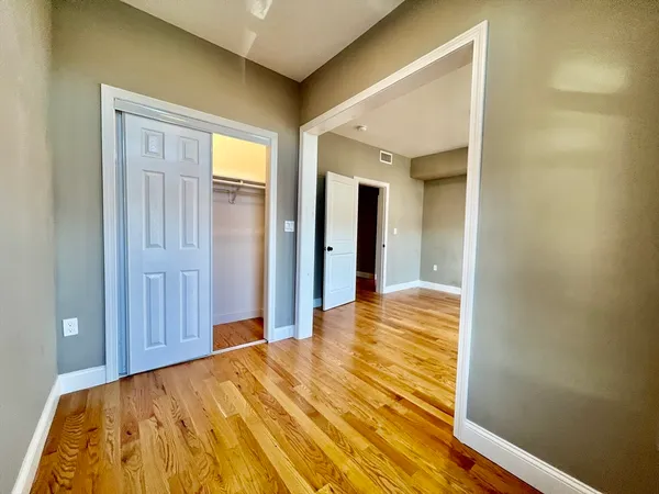 a view of a bedroom with wooden floor and cabinet
