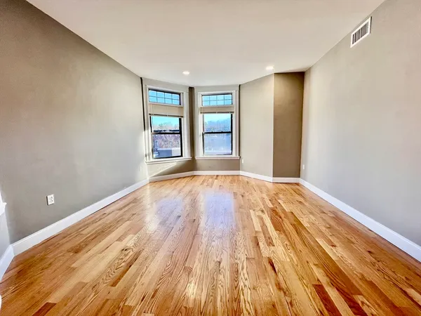 a view of an empty room with wooden floor and cabinets