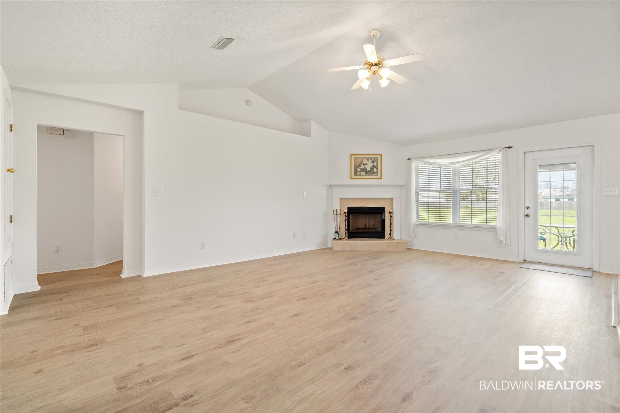 12520 Hunters Chase Foley, AL 36535 - Photo 16 of 32 Unfurnished living room featuring light wood-style flooring, a tile fireplace, ceiling fan, and vaulted ceiling