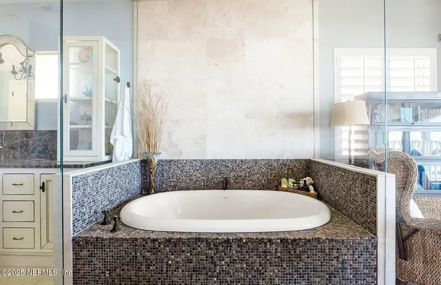 a bathroom with a granite countertop sink a mirror and bathtub