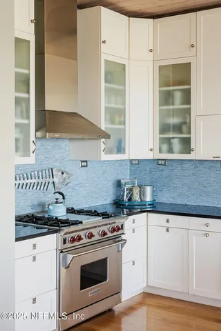a white kitchen with granite countertop a stove and a sink