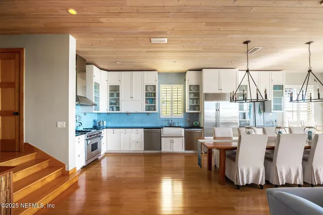 a living room with couches and kitchen view with wooden floor