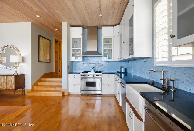 a kitchen with stainless steel appliances a stove a sink and white cabinets with wooden floor