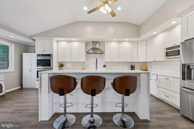 a kitchen with stainless steel appliances granite countertop a stove a refrigerator a sink a dining table and chairs with wooden floor