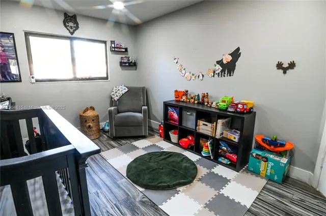 a living room with baby toys and dresser with wooden floor