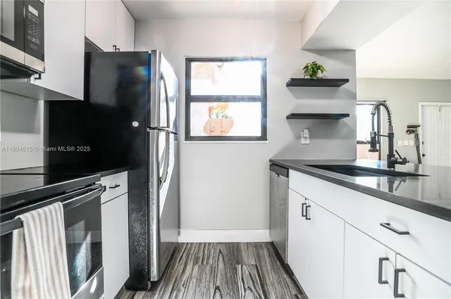 a kitchen with granite countertop white cabinets and stainless steel appliances