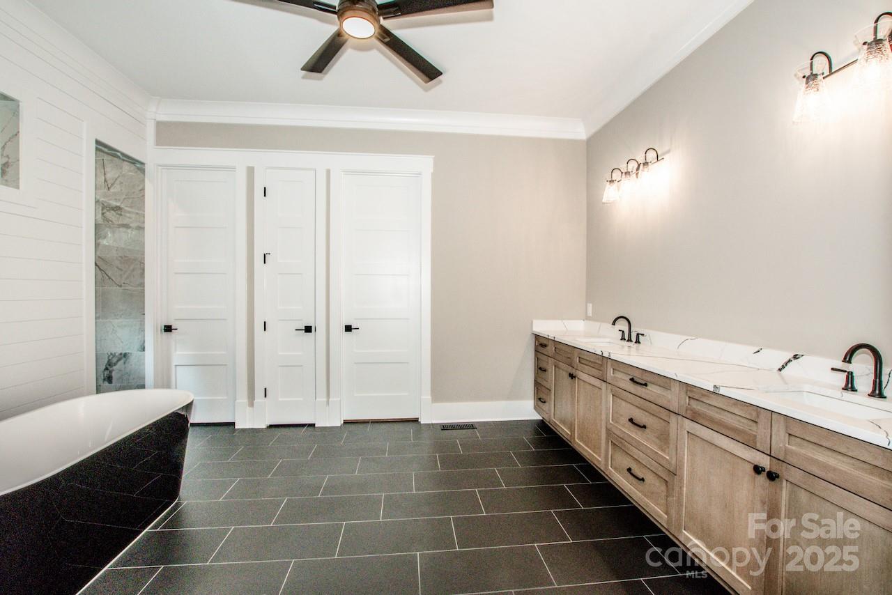 110 Emmaline Court Troutman, NC 28166 - Photo 19 of 40 a bathroom with a double vanity sink a mirror and a bathtub