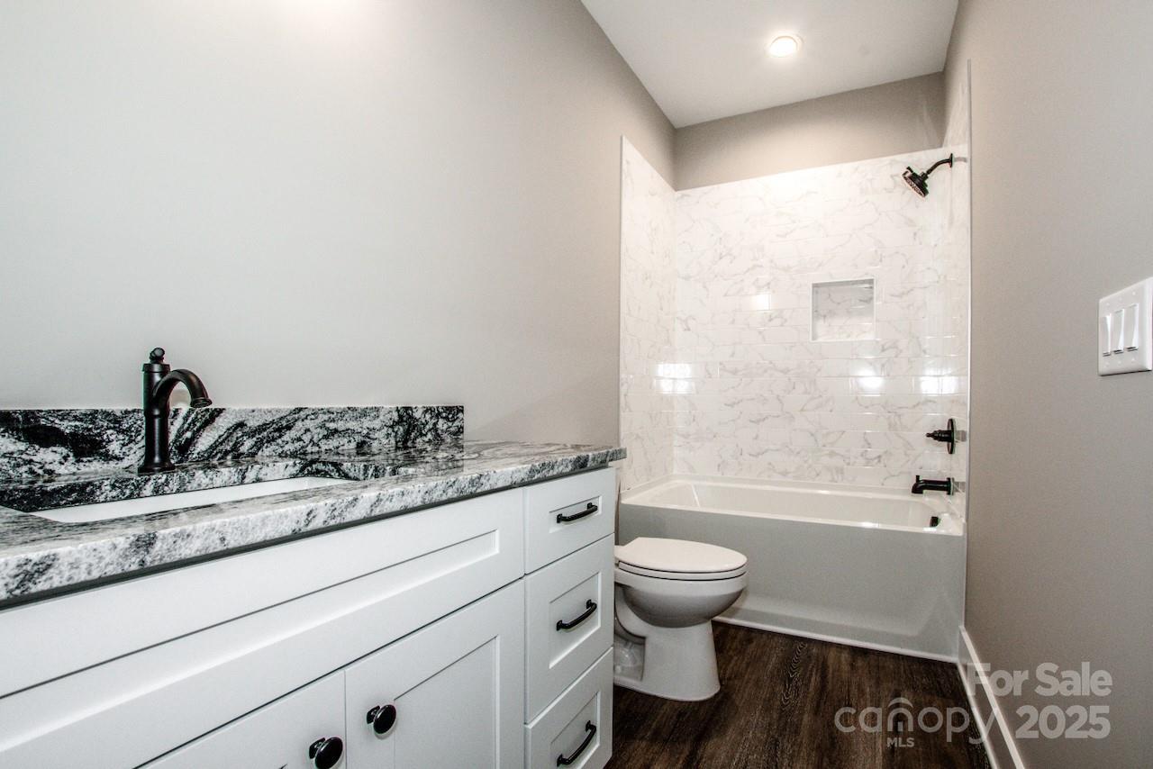 110 Emmaline Court Troutman, NC 28166 - Photo 33 of 40 a bathroom with a granite countertop toilet a sink and a bathtub
