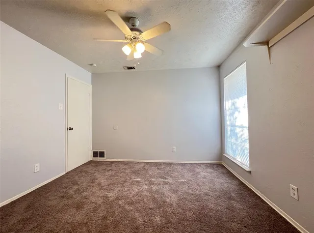 an empty room with windows and fan