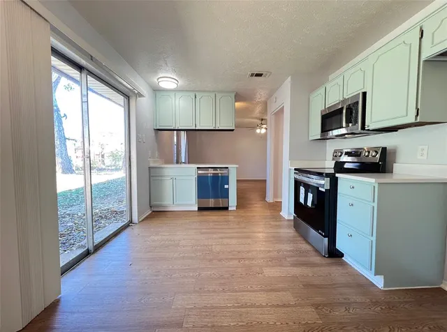 a large kitchen with stainless steel appliances granite countertop a stove a sink and a microwave