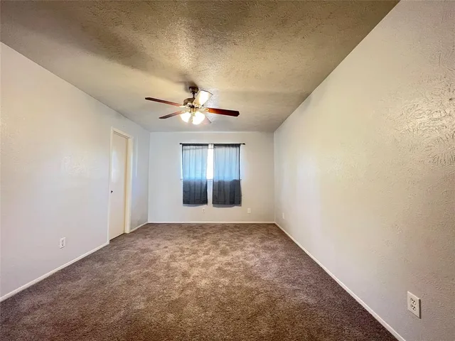 an empty room with windows and chandelier fan