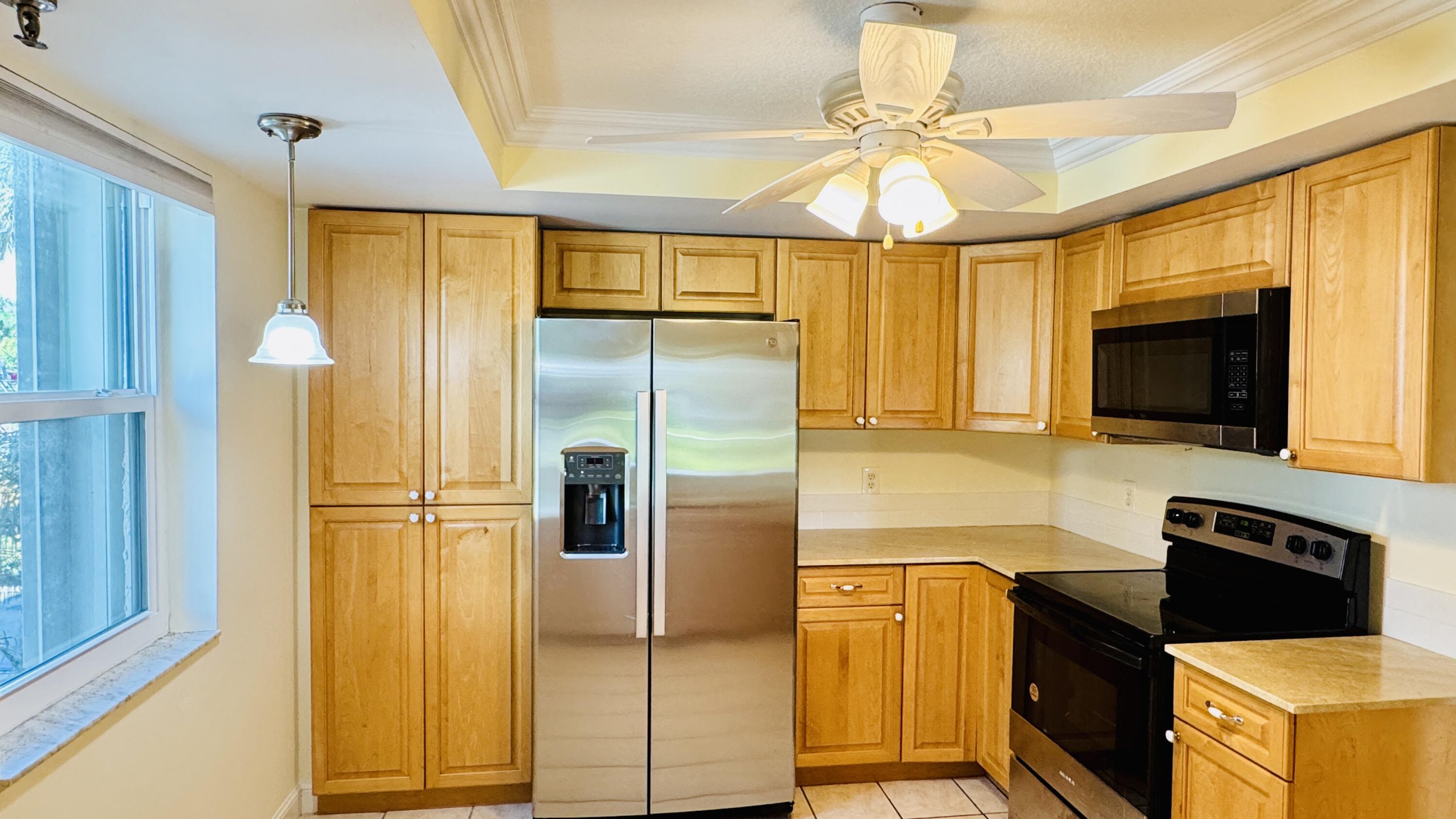 7030 Half Moon Circle, Unit 121 Hypoluxo, FL 33462 - Photo 28 of 74 a kitchen with stainless steel appliances granite countertop a refrigerator a stove top oven a sink and dishwasher