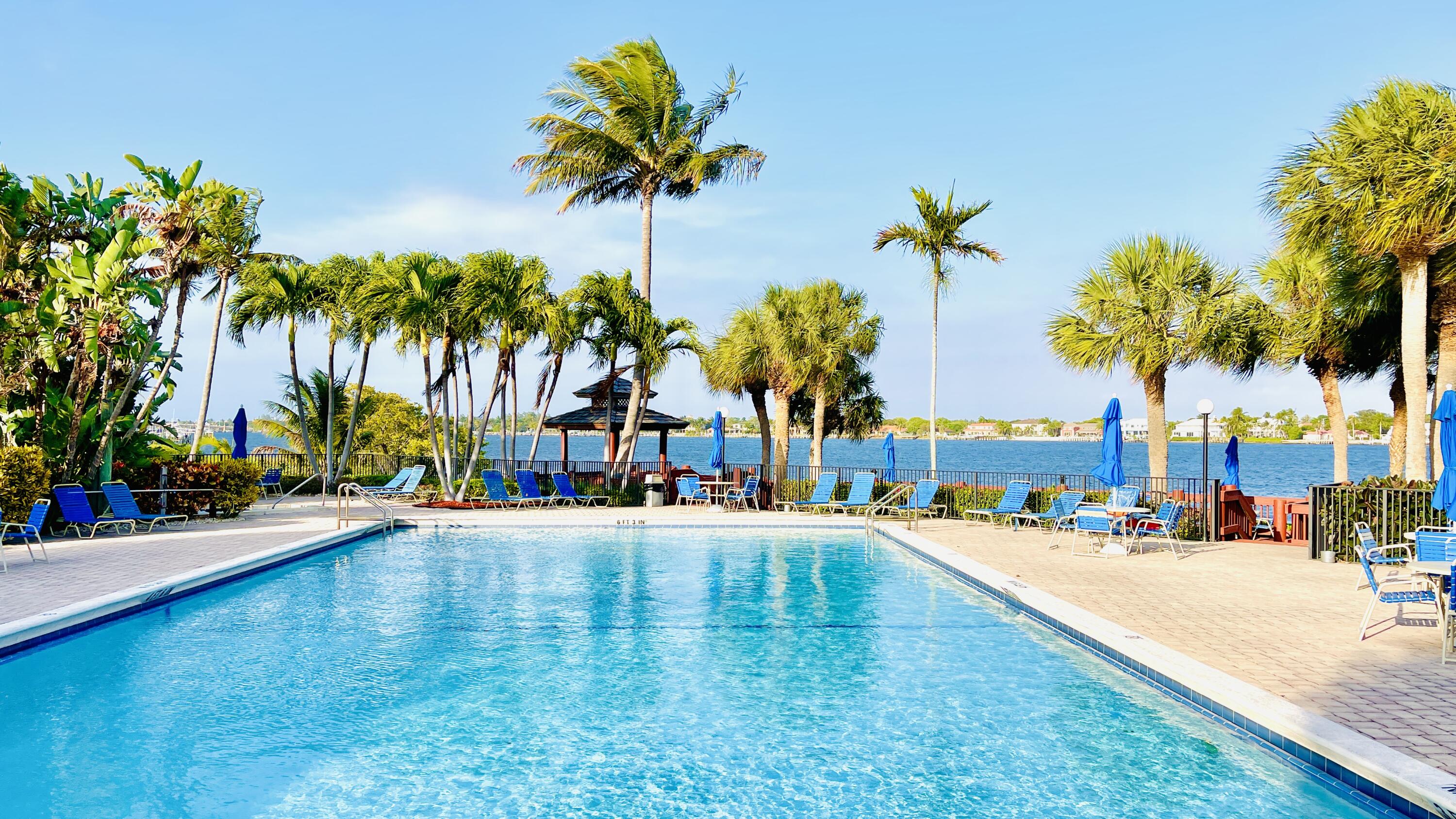 7030 Half Moon Circle, Unit 121 Hypoluxo, FL 33462 - Photo 3 of 74 a view of a swimming pool with a lawn chairs under palm trees