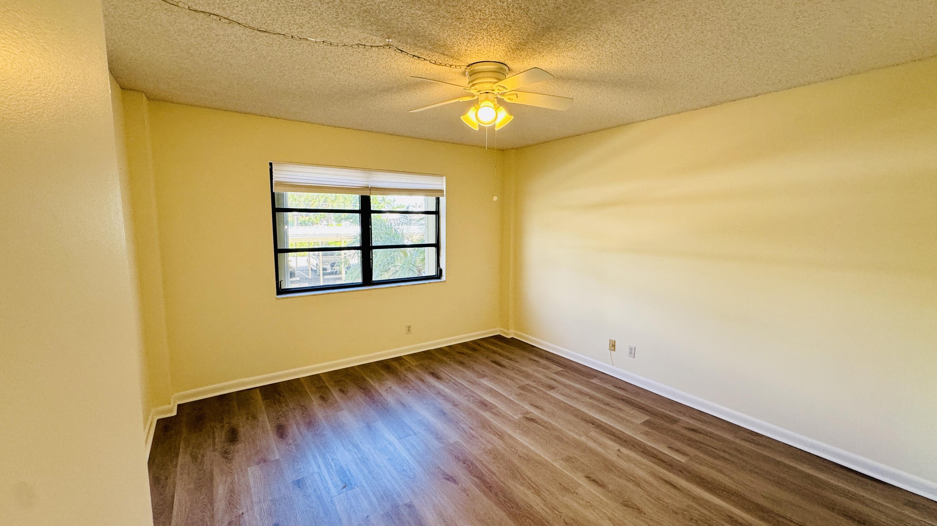 7030 Half Moon Circle, Unit 121 Hypoluxo, FL 33462 - Photo 48 of 74 an empty room with a wooden floor and a window