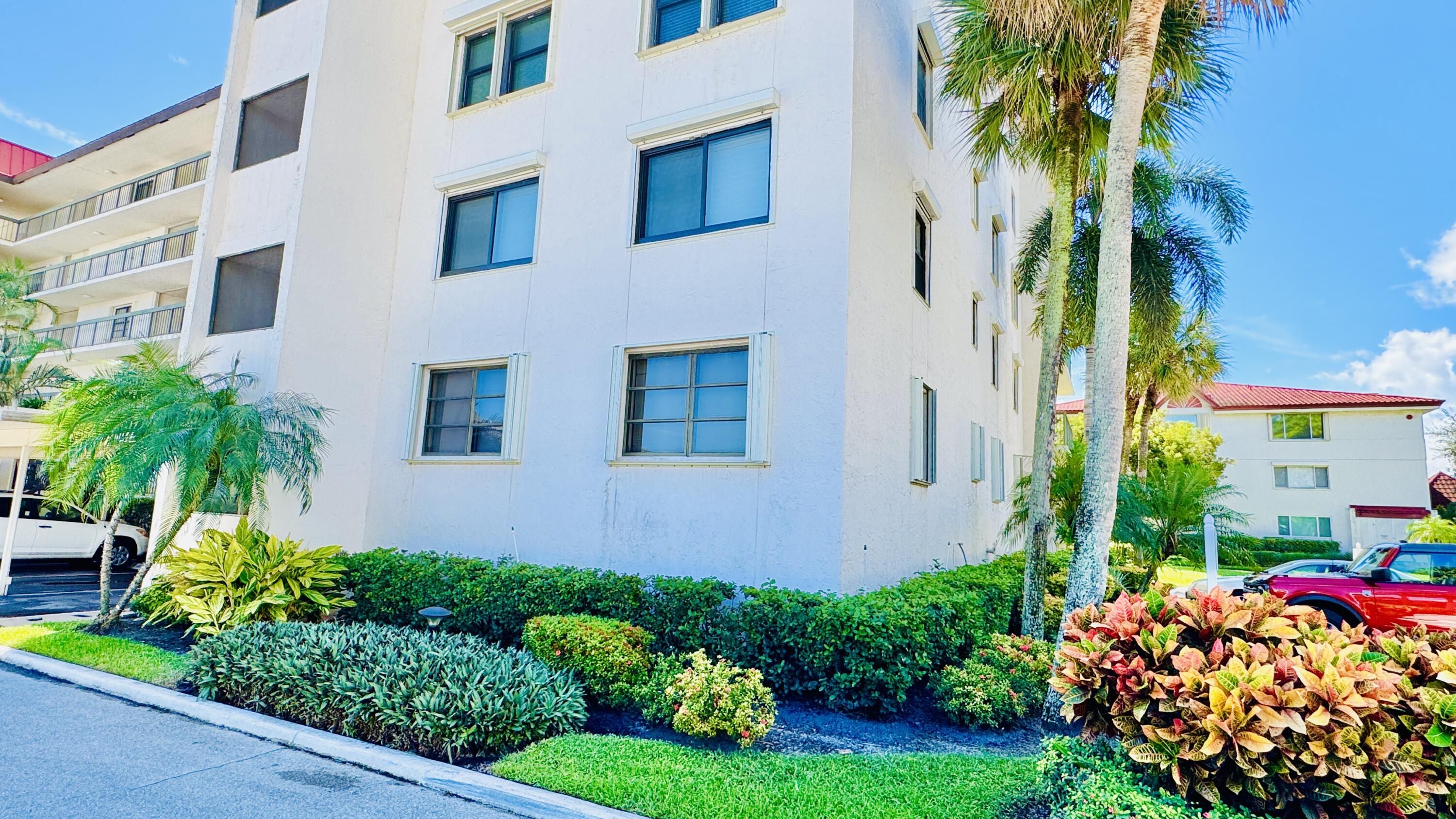 7030 Half Moon Circle, Unit 121 Hypoluxo, FL 33462 - Photo 70 of 74 a front view of a multi story residential apartment building with yard and green space