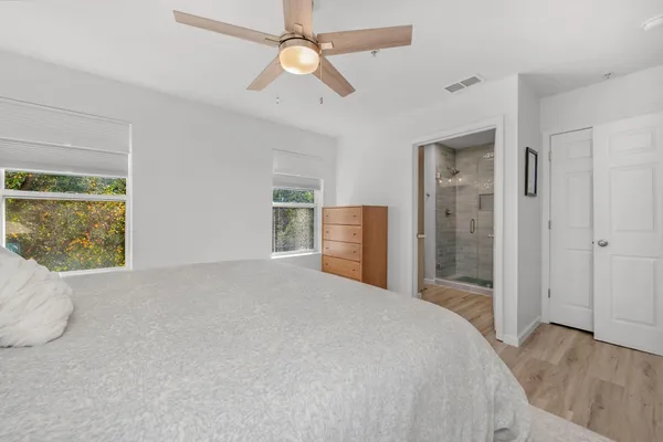 a bedroom with a large bed and a chandelier fan