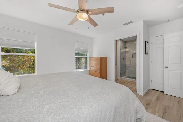 a bedroom with a large bed and a chandelier fan