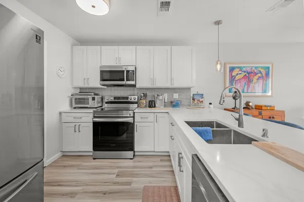 a kitchen with stainless steel appliances a stove a sink a microwave and a refrigerator