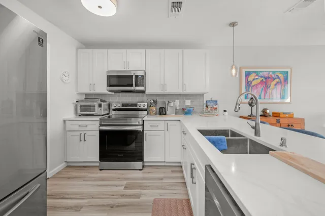 a kitchen with stainless steel appliances a stove a sink a microwave and a refrigerator