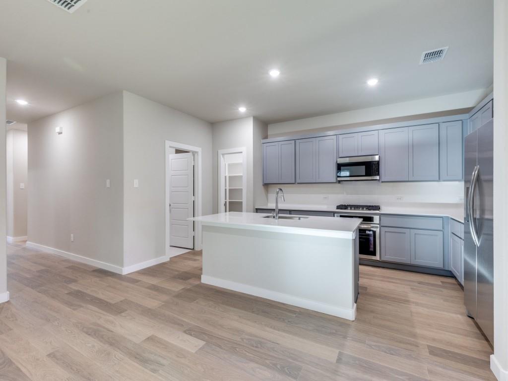 15224 Supreme Street Aledo, TX 76008 - Photo 9 of 25 a kitchen with stainless steel appliances a refrigerator and a stove top oven