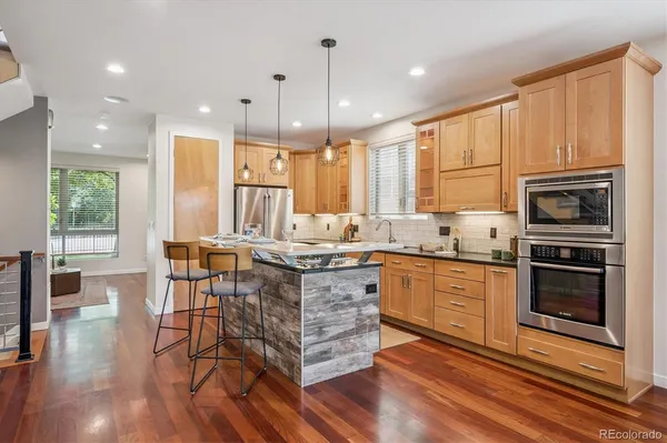 a kitchen with stainless steel appliances granite countertop a stove top oven a sink dishwasher a dining table and chairs with wooden floor