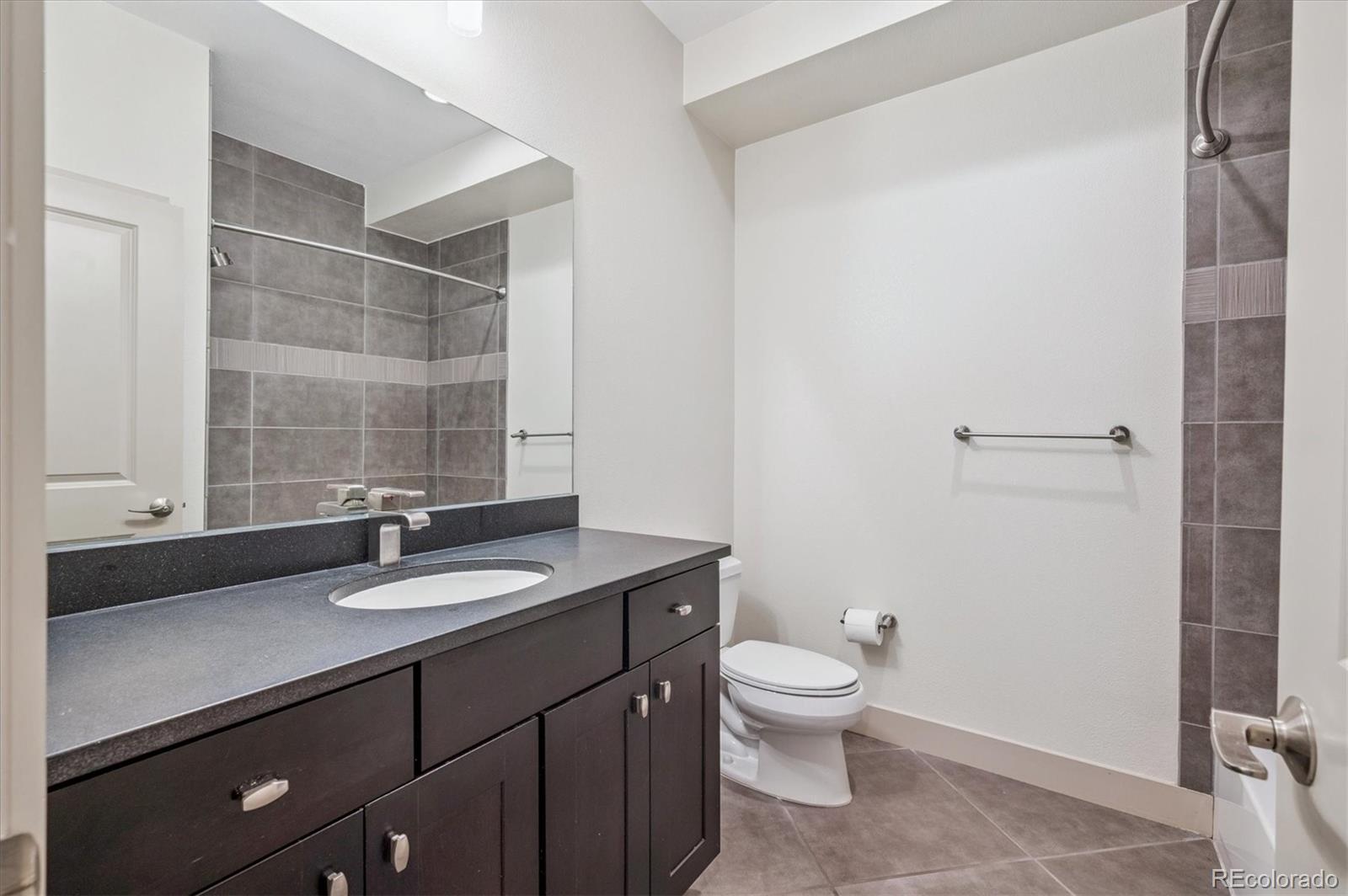 2157 South Logan Street Denver, CO 80210 - Photo 24 of 33 a bathroom with a granite countertop sink toilet a mirror and shower
