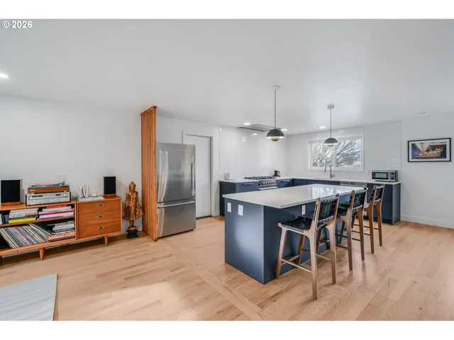 a kitchen with stainless steel appliances kitchen island granite countertop a table chairs and a refrigerator