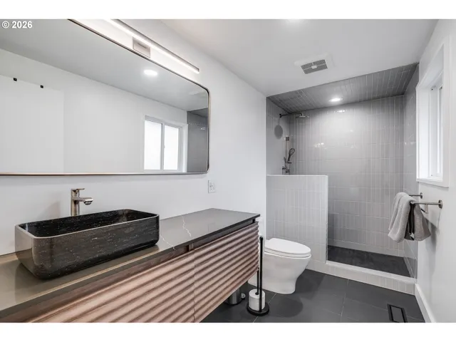 a bathroom with a sink a toilet a mirror and shower