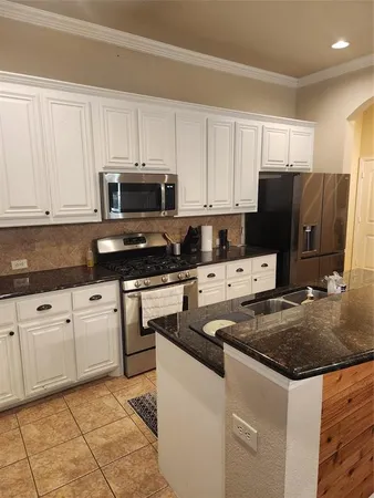 a kitchen with stainless steel appliances granite countertop a stove a sink and a microwave
