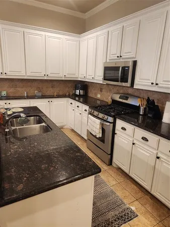 a kitchen with granite countertop white cabinets and stainless steel appliances