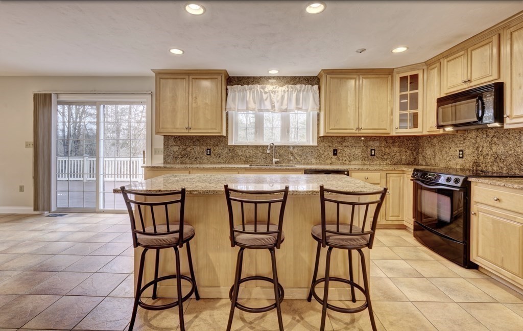 6 Elizabeth Road Auburn, MA 01501 - Photo 13 of 41 a kitchen with stainless steel appliances granite countertop a stove a sink a microwave and a dining table with wooden cabinet
