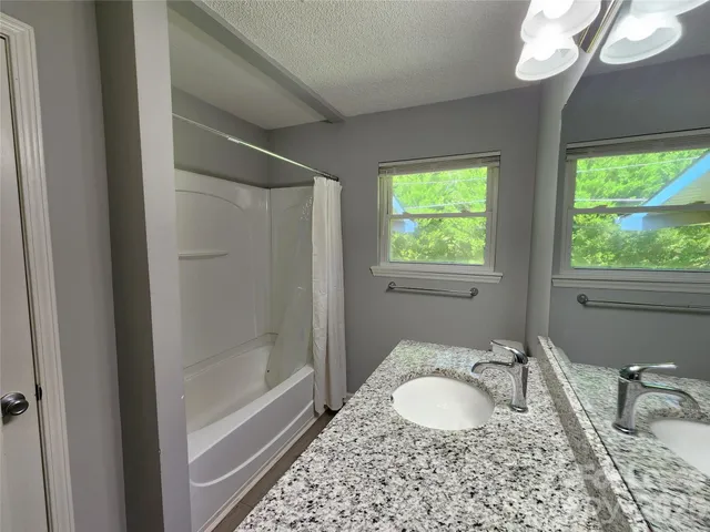 a bathroom with a granite countertop sink a mirror and a bathtub