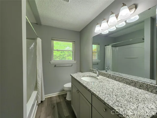 a bathroom with a granite countertop sink a toilet and a mirror