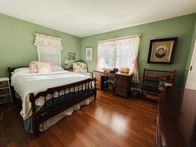 a bedroom with a bed a dresser and wooden floor