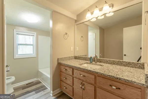 a bathroom with a granite countertop double vanity sink a mirror and a toilet