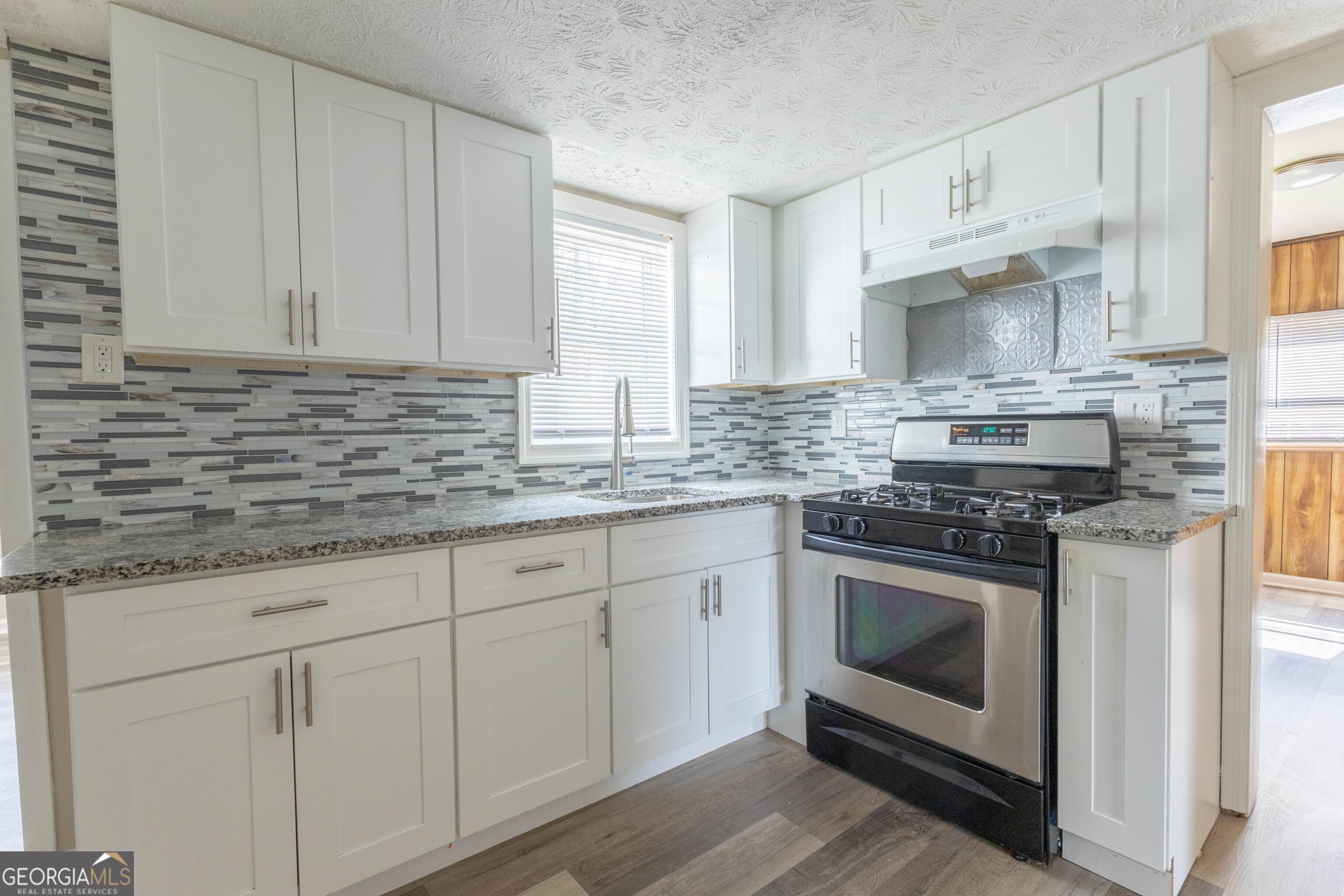 5326 Heardsville Road Cumming, GA 30028 - Photo 13 of 22 a kitchen with stainless steel appliances granite countertop a stove a sink and white cabinets