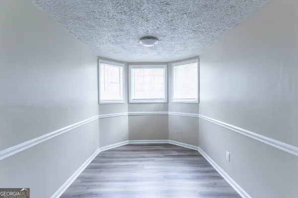 a view of an empty room with wooden floor and window