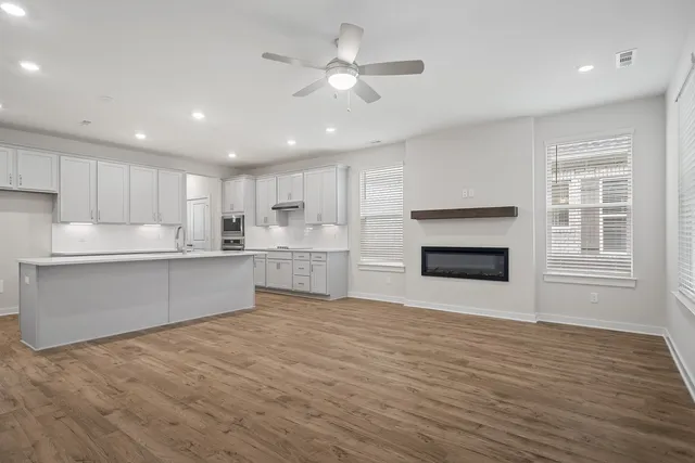 a large kitchen with kitchen island a sink wooden floor and stainless steel appliances
