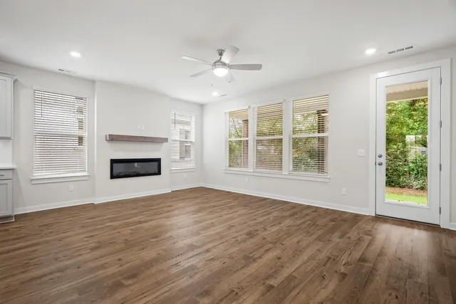 a view of an empty room with window and wooden floor