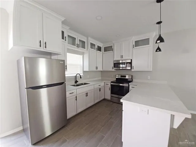 a kitchen with a refrigerator a stove top oven a white cabinets and wooden floor