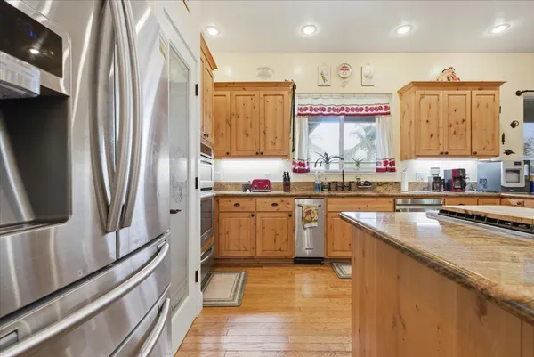 a kitchen with granite countertop a sink cabinets stainless steel appliances and a window