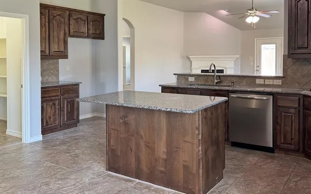 a kitchen with kitchen island granite countertop a sink stove and refrigerator