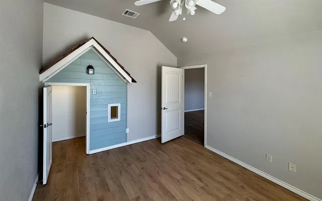an empty room with wooden floor chandelier fan and entryway