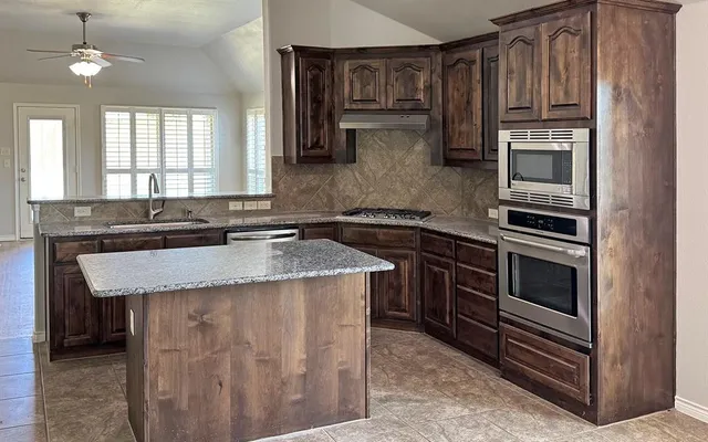 a kitchen with granite countertop stainless steel appliances and wooden cabinets