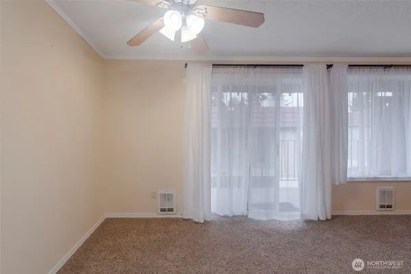 an empty room with windows and chandelier fan