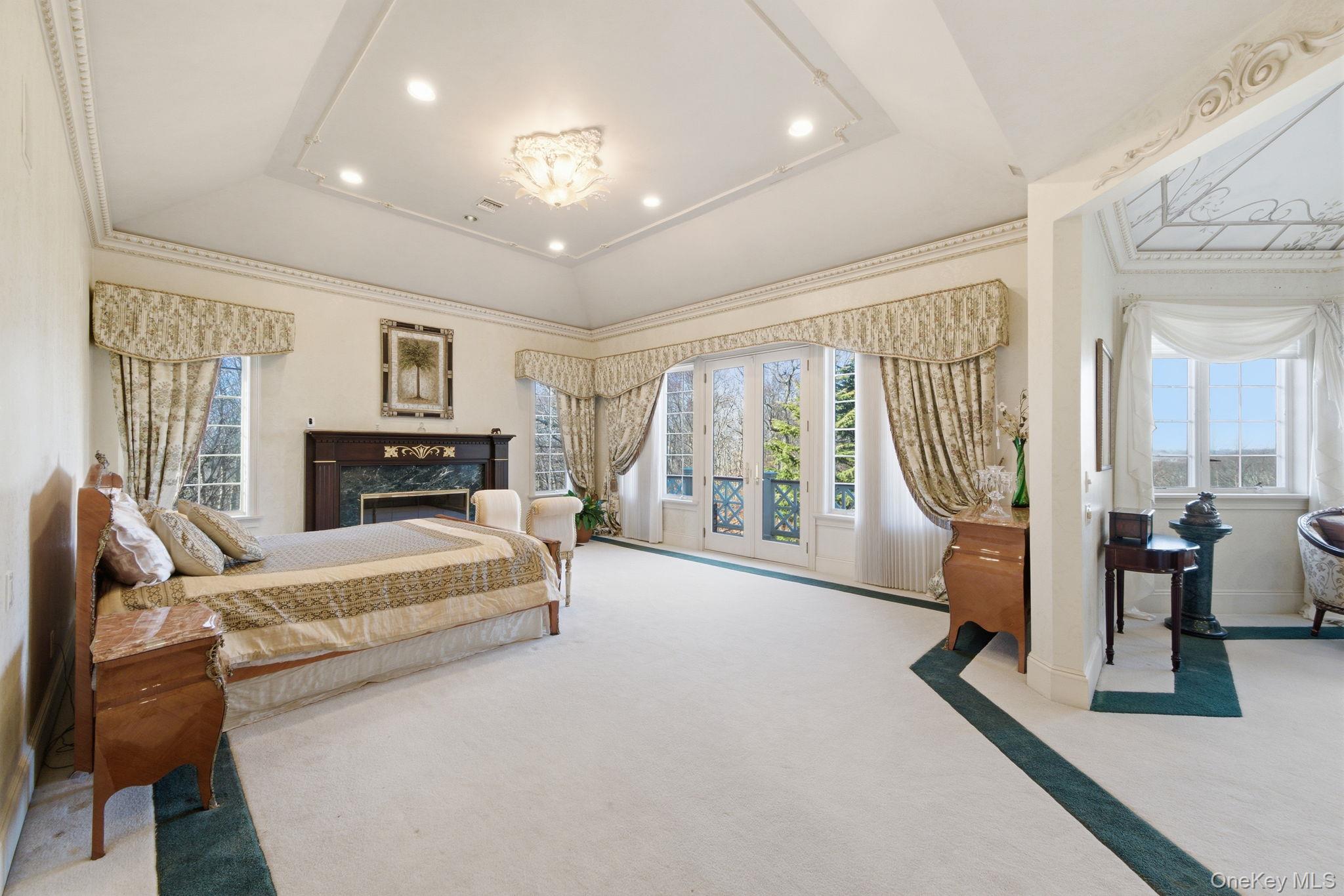 19 Cobblestone Court Centerport, NY 11721 - Photo 25 of 45 a spacious bedroom with a bed a couch and large window with balcony view
