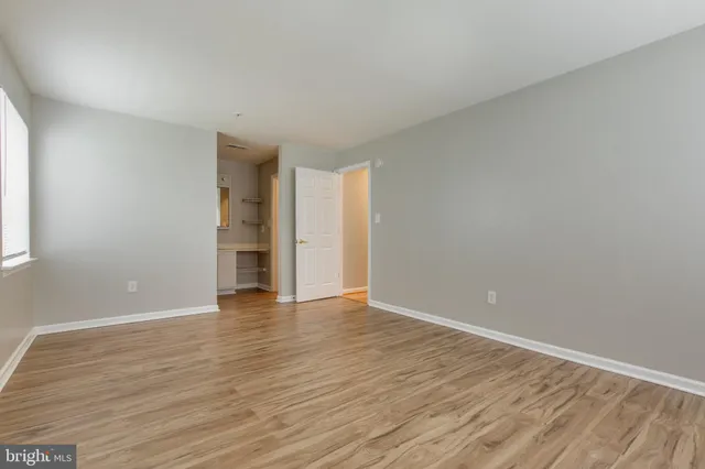 a view of an empty room with wooden floor and closet